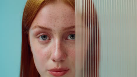 woman with red hair and freckles behind striped panel