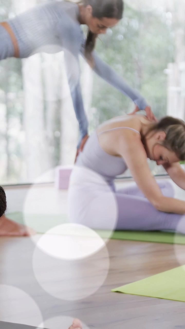 Video verticale: Studente che si allunga per toccare il piede, allenatore che si avvicina e guida lo stretching con le mani su un tappetino da yoga.
