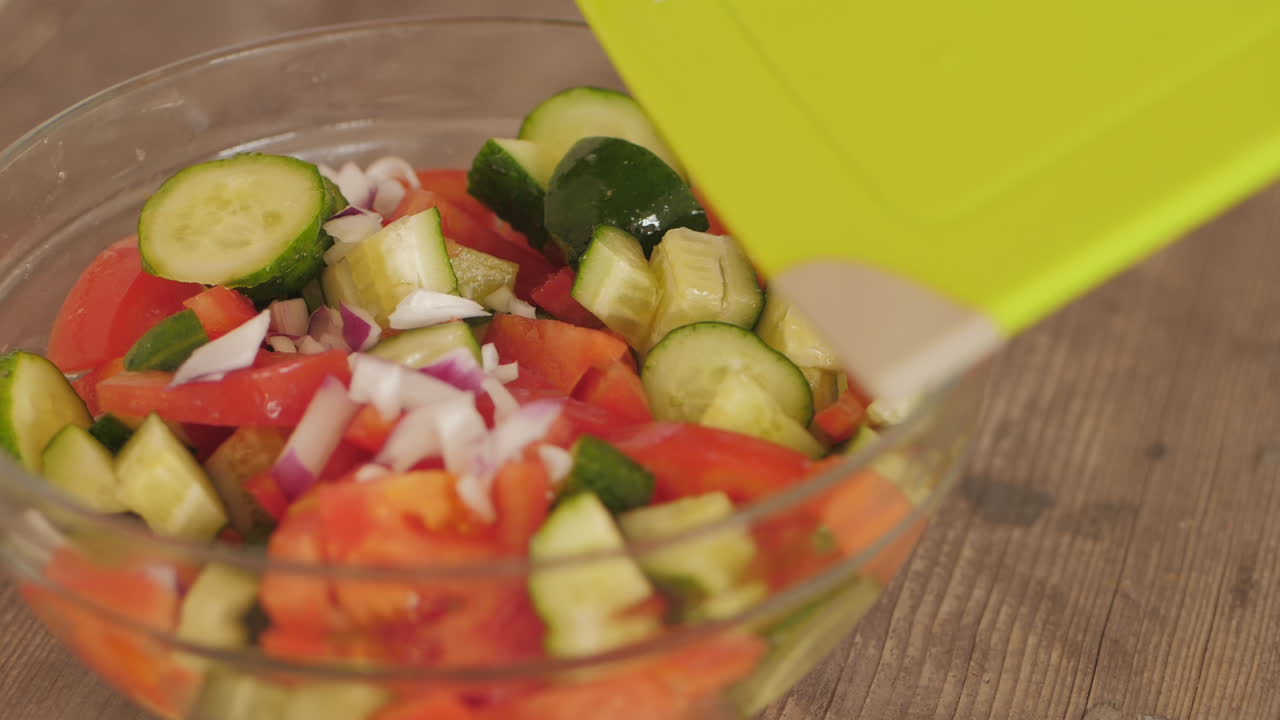 잘게 썬 양파는 도마에서 잘게 썬 토마토와 오이 그릇에 넣습니다.