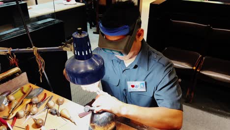 a worker making gold design using tools under the light