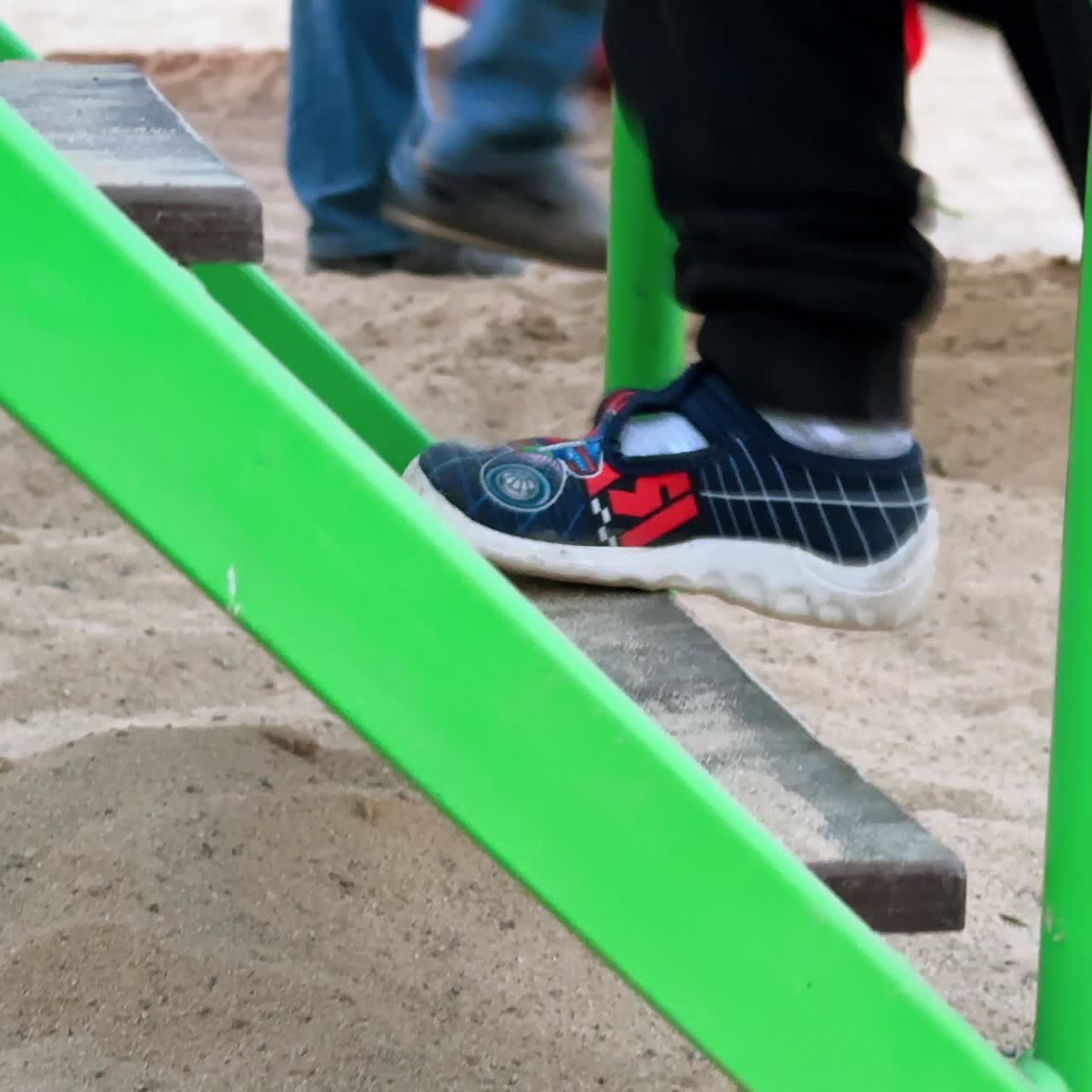 Little child's feet go up by the stairs. Unrecognized kid climbs the steps on the playground
