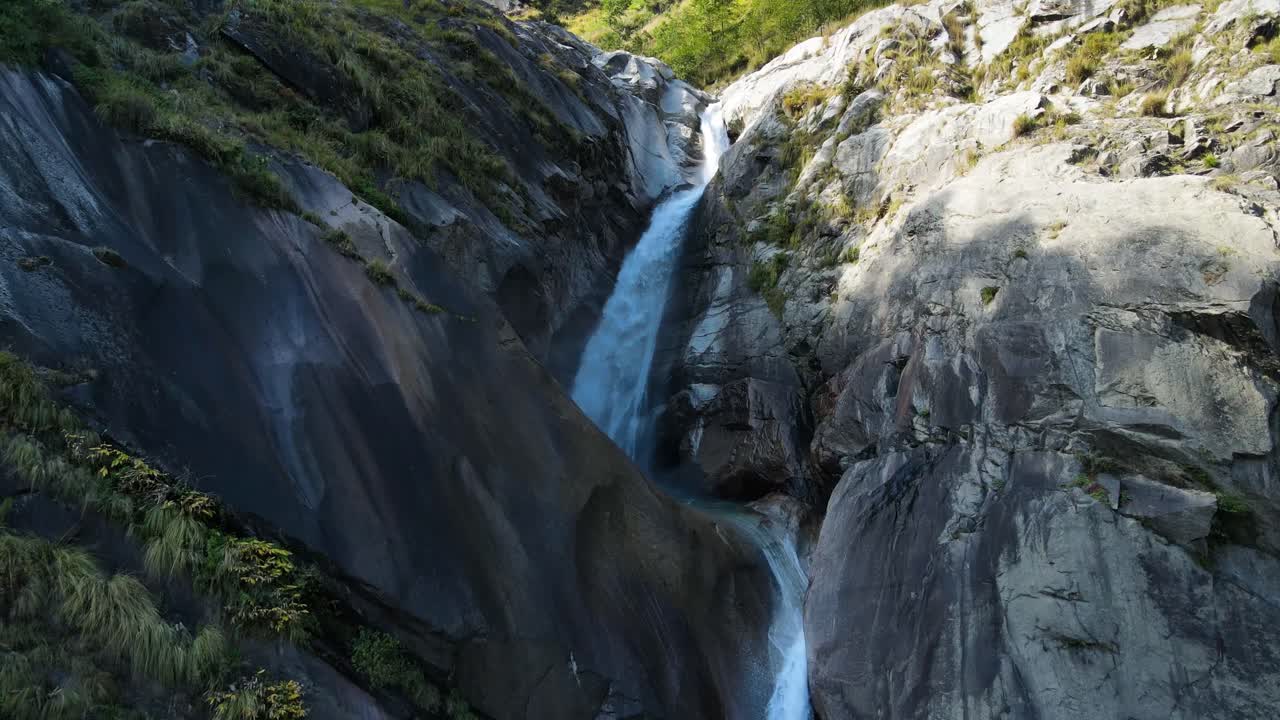 una toma aérea de un dron que destaca la belleza de una cascada rugida que se sumerge en un valle rocoso.
