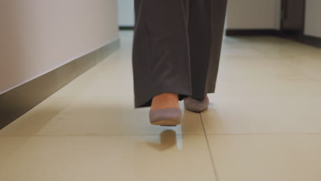 close-up of businesswoman's feet in gray heels walking through office corridor, professional attire, confident stride, modern office setting, stylish businesswoman in formal shoes