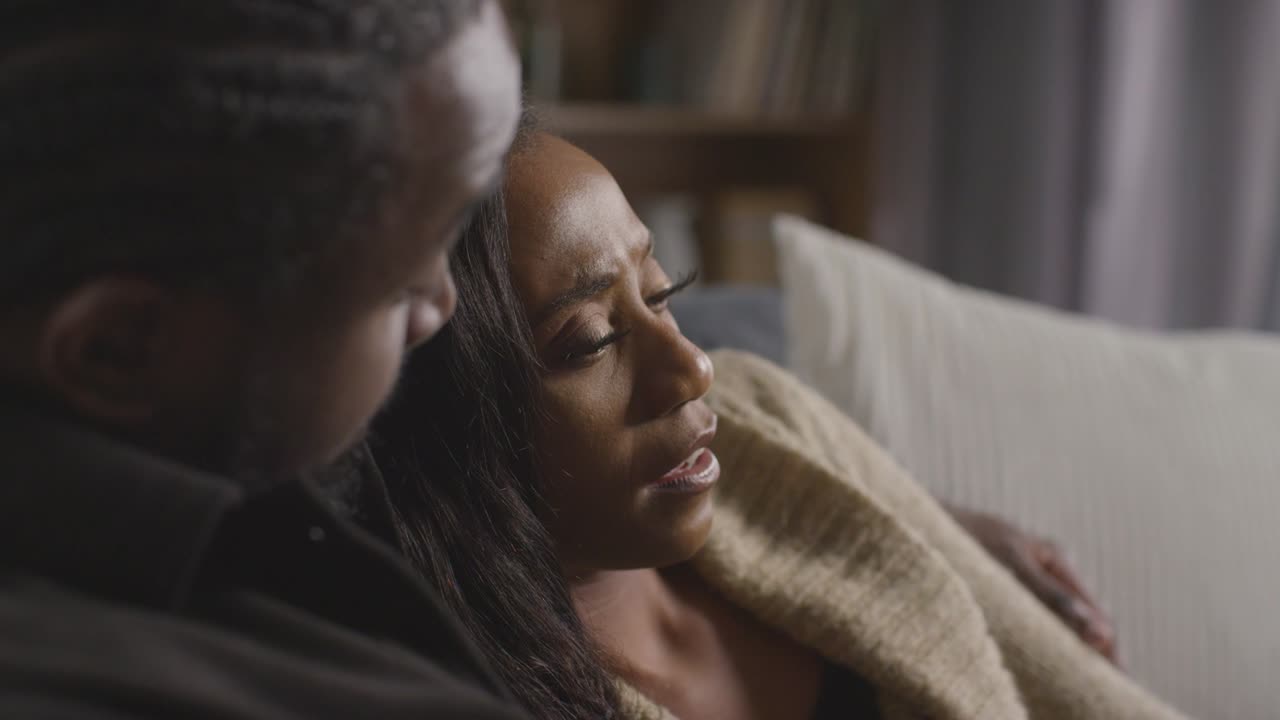 pareja en casa sentada en el sofá en el salón con un hombre reconfortando a una mujer infeliz 6