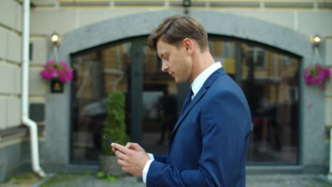 Business-man-texting-on-smartphone-outside.-Thoughtful-man-walking-at-street