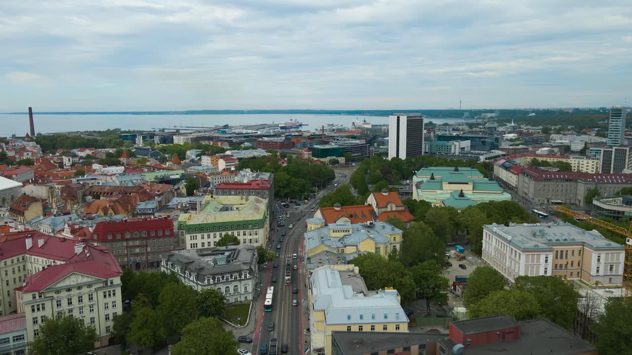 Gorgeous Aerial drone view of Tallinn old city and central town medieval and modern buildings where cars, trams and buses are driving in between during a cloudy day. Tallinn harbor also visible.