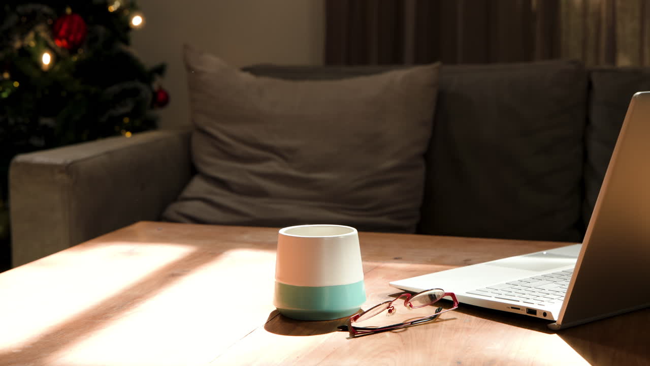 Cozy living room with laptop, coffee mug, and Christmas tree in background