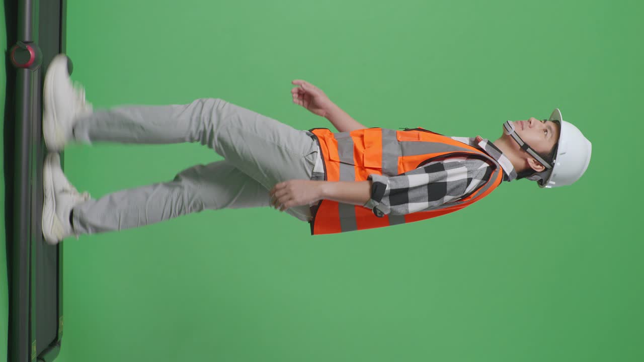 안전 헬을 입은 아시아 남성 엔지니어가 녹색 스크린 배경 스튜디오에서 는 동안 주위를 둘러보고 있습니다.