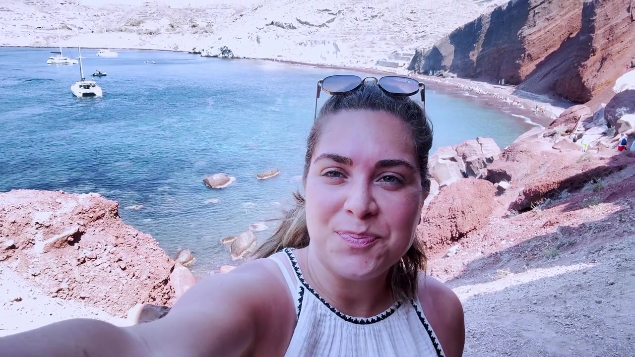 Vlogger che registra un video selfie sulla spiaggia rossa a Santorini, Grecia