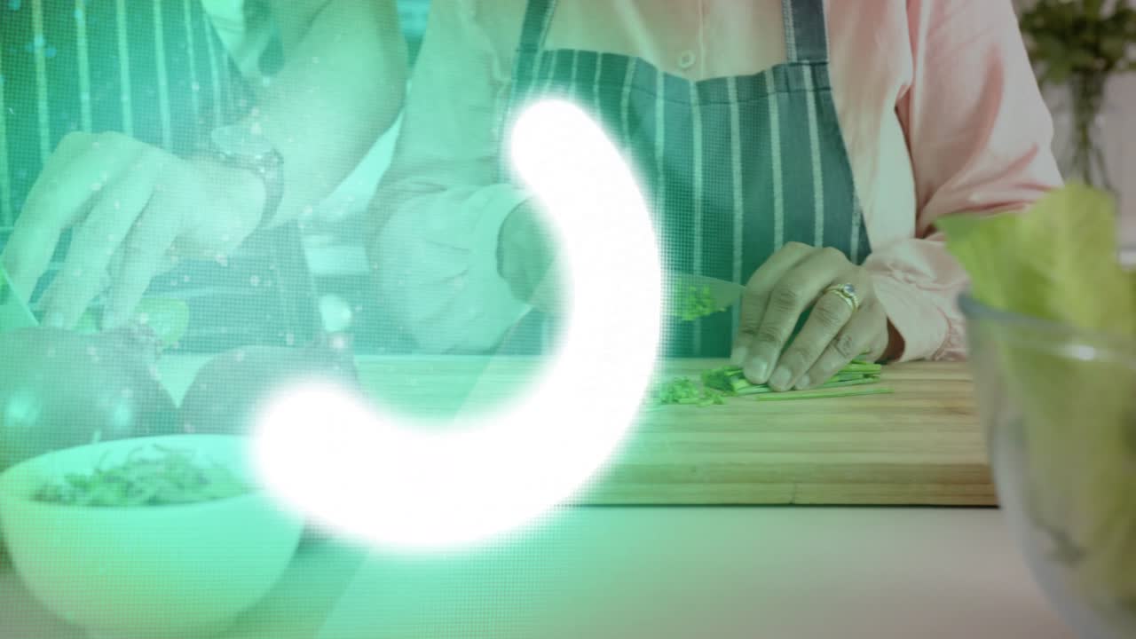 Man chopping herbs while woman slicing onions, green circle sweeping, blocking view for meal prep