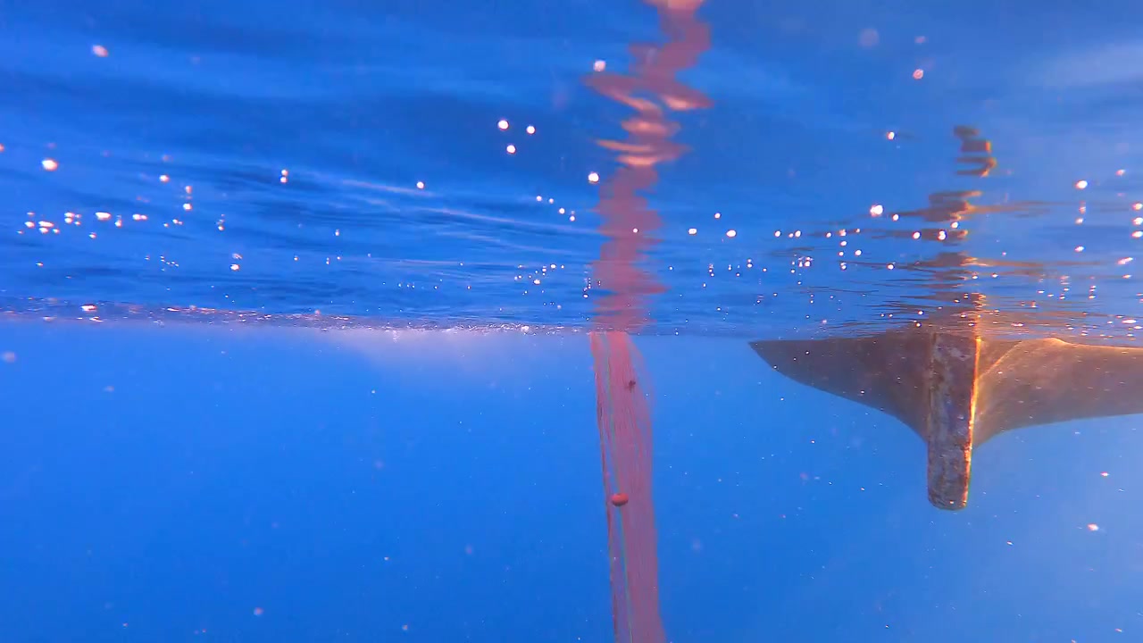 Undervannsvy av en båtkjøl og bobler i havet