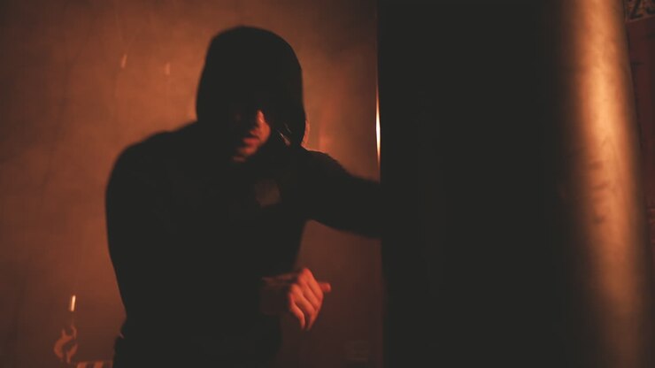 Sportivo con felpa con cappuccio colpisce il sacco da boxe