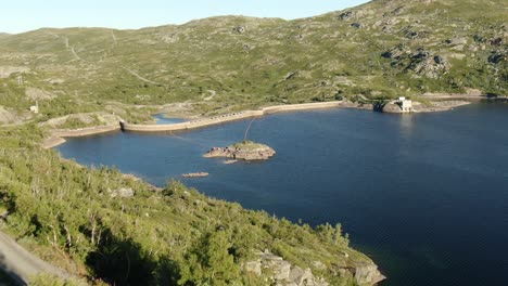 aerial reveal shot of an electric power plant located on the dam in norway on a sunny day