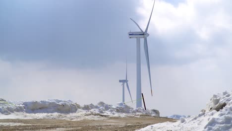 wind power turbines are seen in the half snow-covered ranch, italy