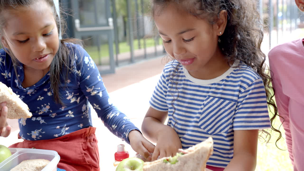 In school, children eating lunch together, enjoying sandwiches and apples