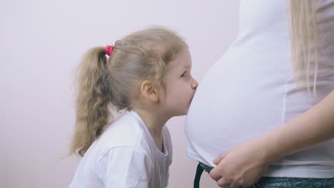la niña besa el vientre de la mamá esperando el nacimiento del hermano en la habitación