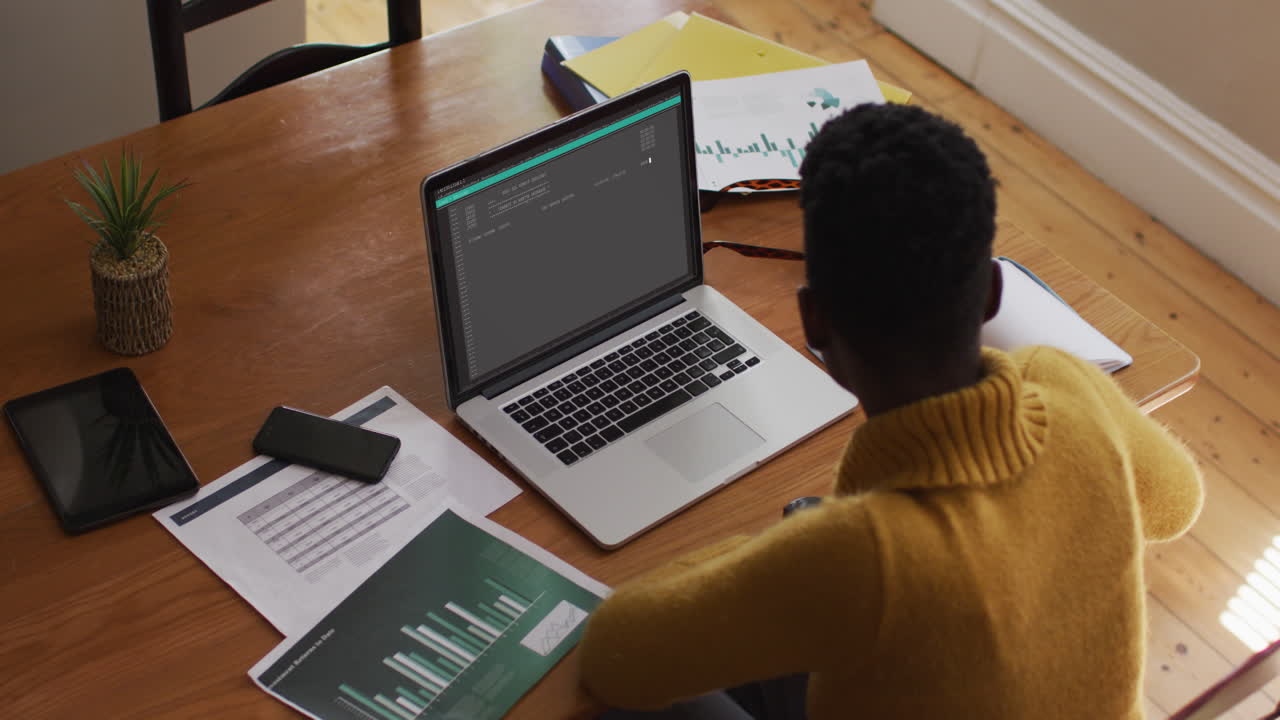 African american man sitting at desk coding data on laptop