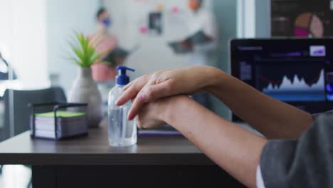 Close-up-view-of-woman-using-hands-sanitizer-at-modern-office