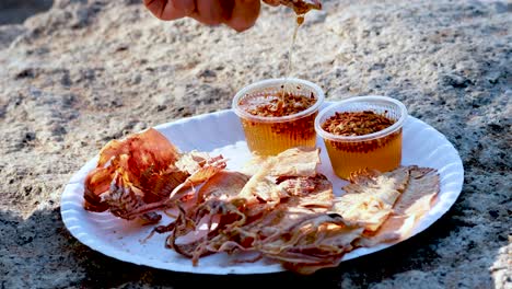 hand dipping squid into sweet sauce on plate