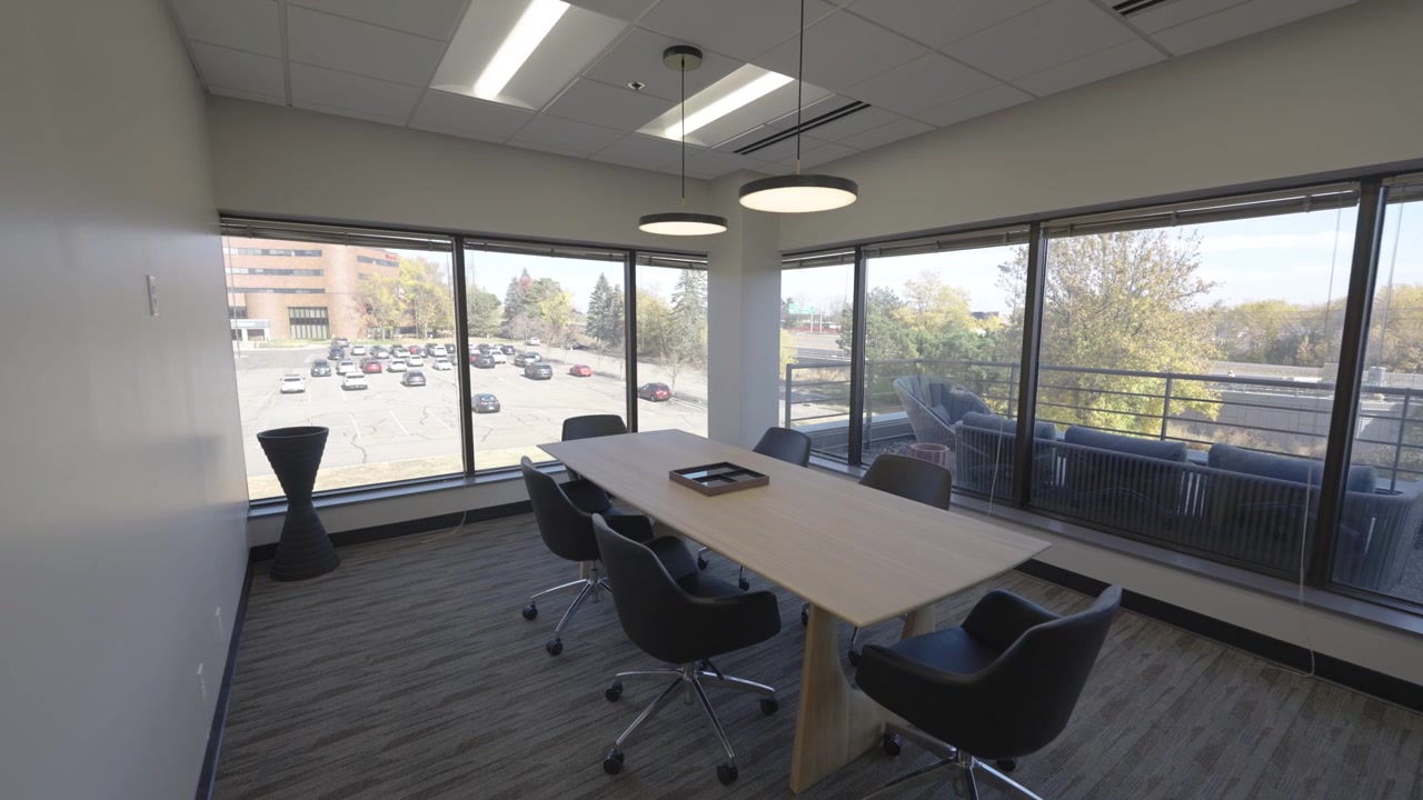 Bright and professional conference room featuring a sleek table, ergonomic chairs, and floor-to-ceiling windows.