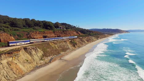 el tren viaja a lo largo de los acantilados en del mar, san diego, california, ee.uu. - toma aérea de un dron