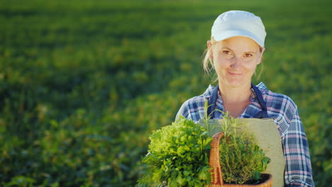 woman farmer with basket of greens and spices standing on the field