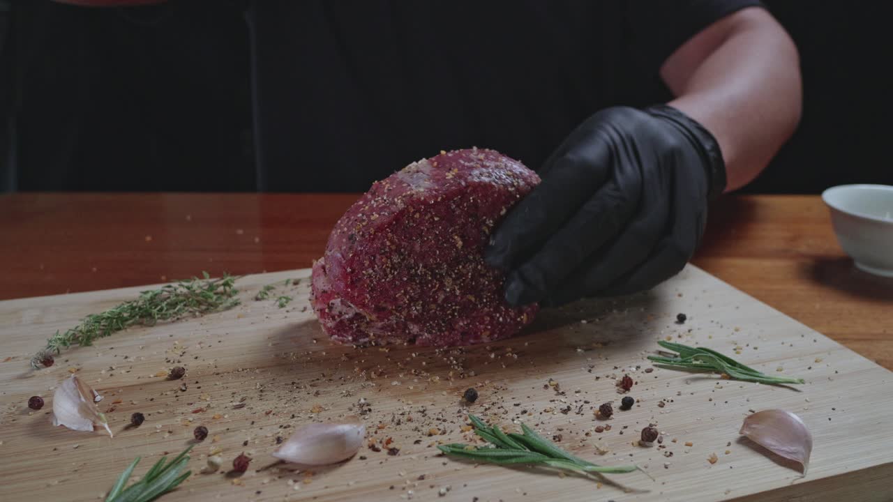 Chef seasons raw fresh tenderloin steak on a wooden cutting board, slow motion, close up
