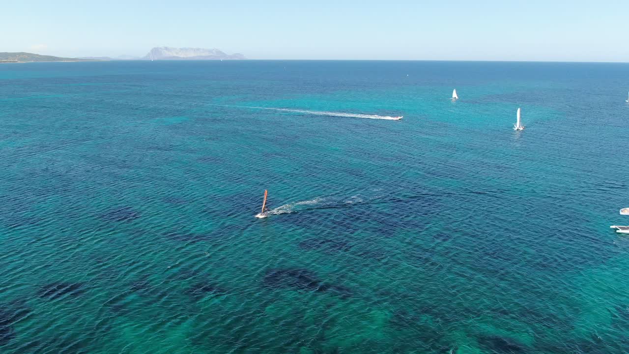 This video follows a forward motion as it captures rich blue water in Sardinia, Italy while capturing life on the water by watching passing boats and racing  water sports