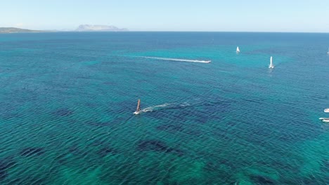 this video follows a forward motion as it captures rich blue water in sardinia, italy while capturing life on the water by watching passing boats and racing  water sports