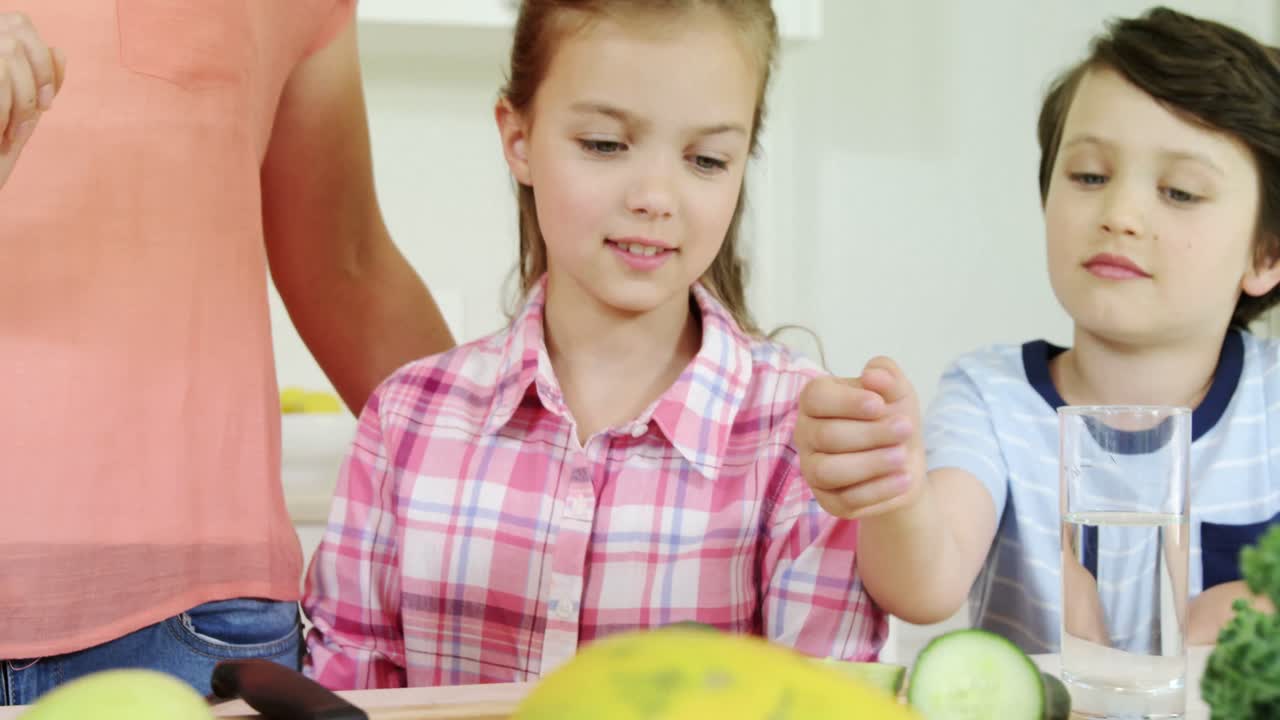 Madre che aiuta i bambini a preparare un frullato di verdure