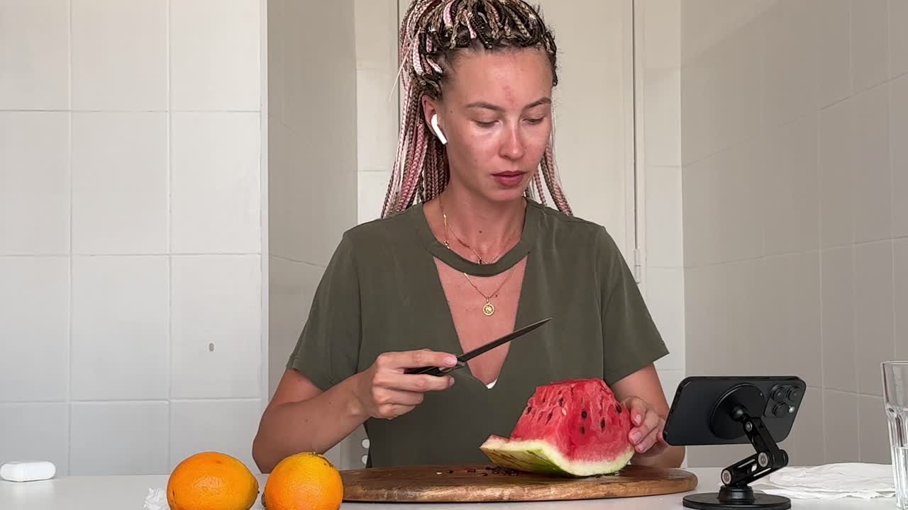Young Woman Cutting and Eating Watermelon in Kitchen