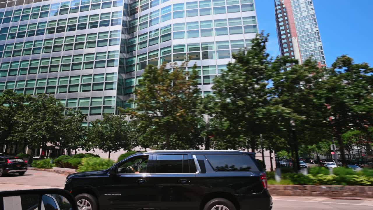 Nueva York, EE. UU., 9 de agosto de 2025: Modernos edificios de oficinas de cristal vistos a través de los árboles verdes de la ciudad. Paisaje urbano con arquitectura de gran altura y exuberante vegetación bajo un cielo azul claro