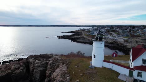 lighthouse on a rocky island and a quaint village on the water during dusk