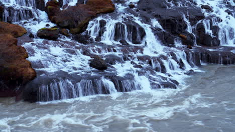 waterfall cascading down to hvita river through mossy rocks