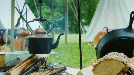 the kettle boils in native american camp in the forest food is being prepared in the foreground trad