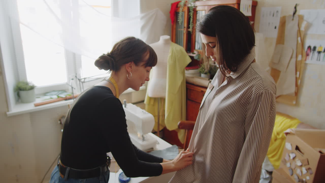 costurera y cliente femenino probando camisa en el atelier