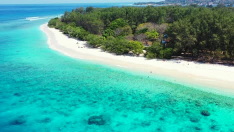 tourists swimming in the turquoise calm sea water on tropical island with shite sand beach