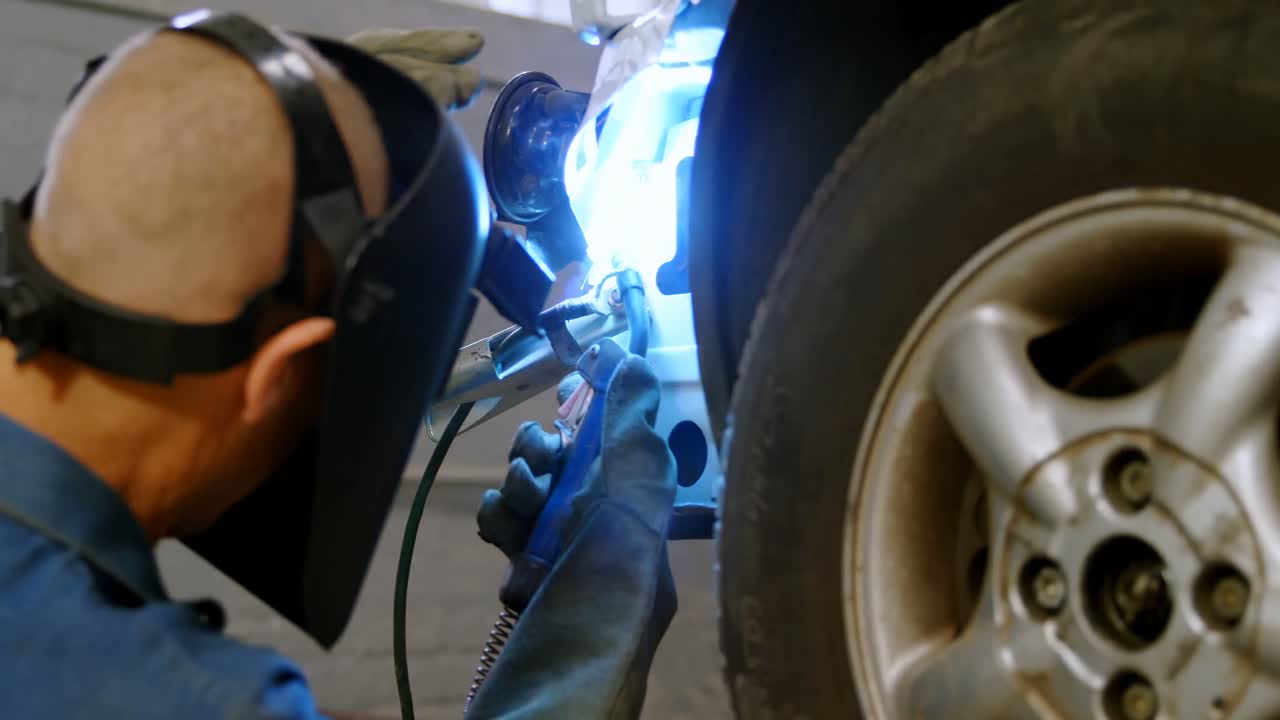 Mechanic using wielding torch on a car 4k