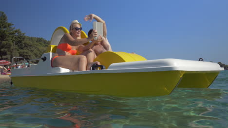 Family-in-pedal-boat-taking-selfie-with-pad