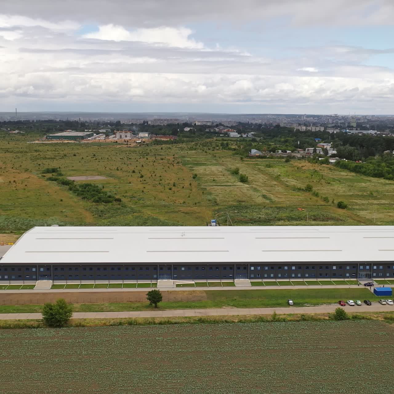 Contemporary business building. View from above on a modern industrial building surrounded by natural fields. Aerial view. Motion camera forward.