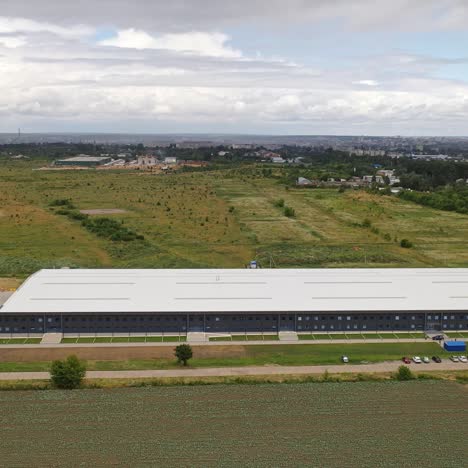 contemporary business building. view from above on a modern industrial building surrounded by natural fields. aerial view. motion camera forward.