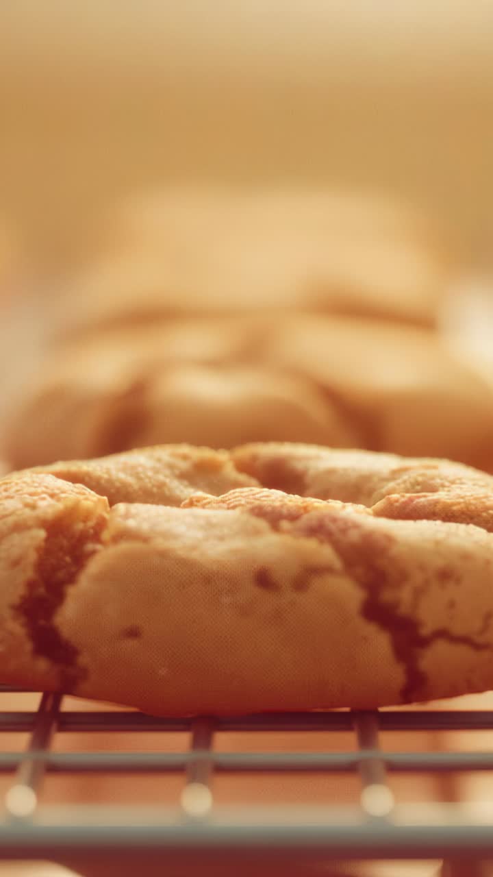 Vertical video: Opening sequence panning cracked cookie across wire rack, revealing golden cookies