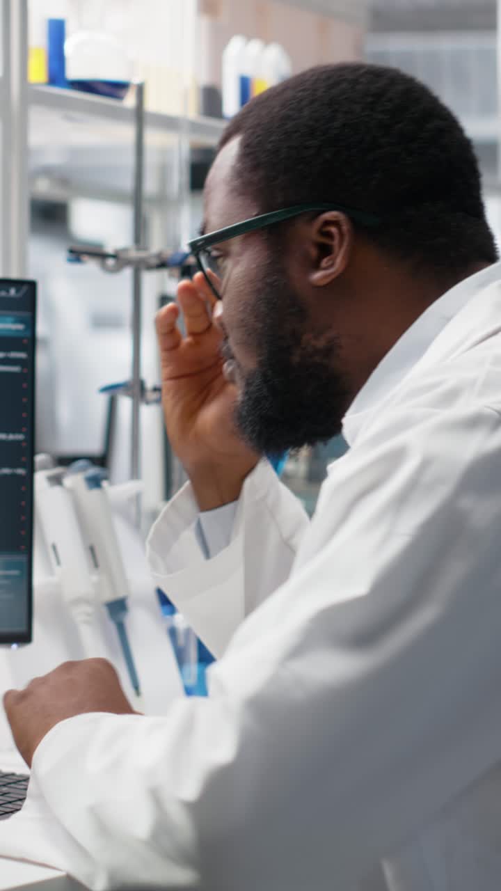 Vertical video Molecular biologist uses computer displaying DNA data, removing eyeglasses