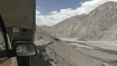 a convoy of indian army trucks ahead of vehicles crossing the roads of ladakh in mountain roads