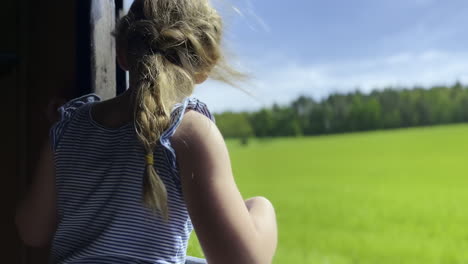 a girl in an open window of a moving train