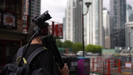 close up of a young caucasian man is walking with his backpack and camera tripod on his back in the streets of the business district canary wharf in london in autumn