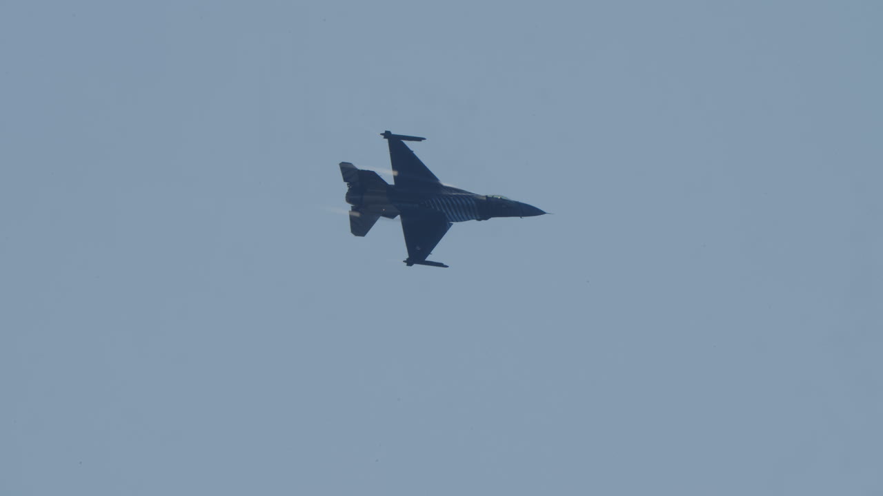 F-16 stridsflygplan som flyger och manövrerar på blå himmel
