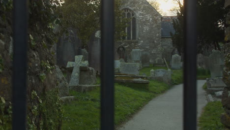Graveyard-with-old-tombstones,-sliding-shot-behind-bars,-Mylor-Churchtown