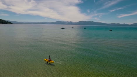 an aerial over a woman paddling a kayak across lake tahoe 2