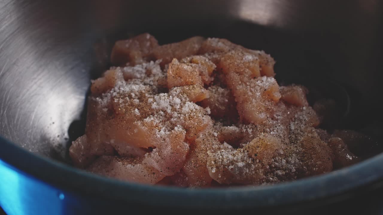 날것으로 썬 닭 가슴살이 추가된 다음 하나의 다채로운 향신료가 추가된 빈 금속 그릇에 극단적으로 근접한 다음 나무 숟가락으로 그릇 주위를 잘 섞습니다.